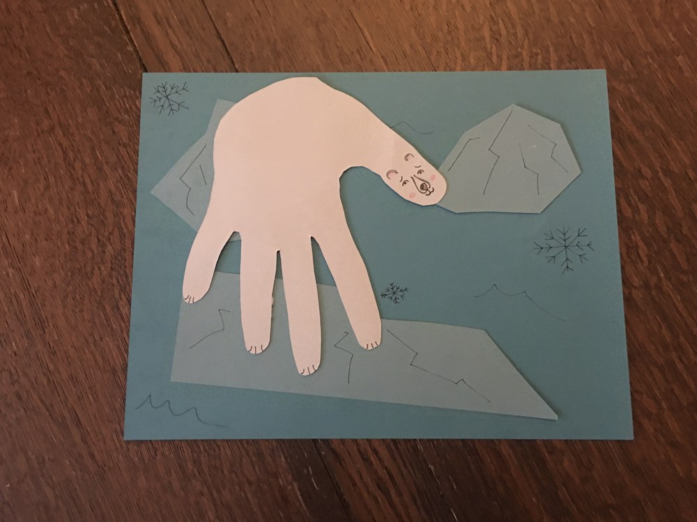 A child's paper craft artwork using the outline of a hand to make a polar bear.