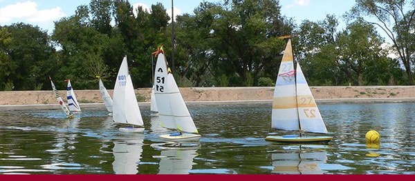 A row of small white toy boats floating on the surface at Tingley Beach.