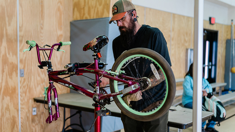 A man examines a bike in the process of being assembled on a table.