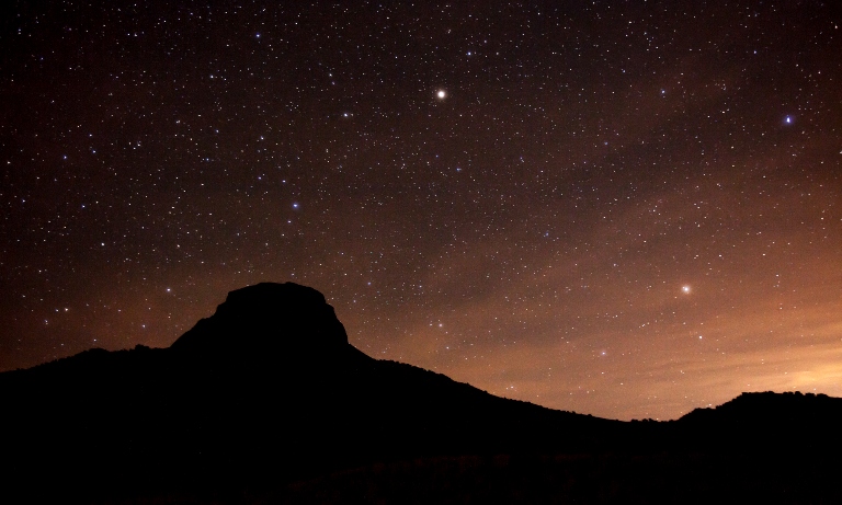 A mesa at sunset with stars above.