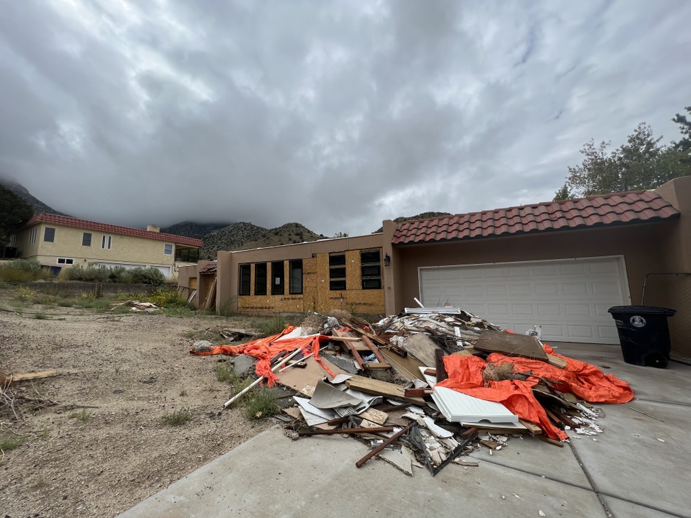 A dilapidated house with a scrap pile in the front yard.